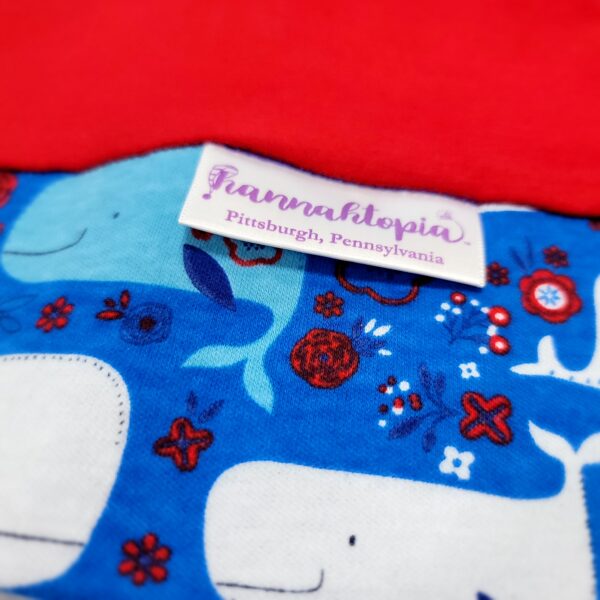 Red length with Blue band decorated with blue and white happy whales NillyNoggin EEG Cap close up of fabric