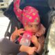 girl wearing a pink pineapple nillynoggin getting an eeg and drinking from a sipping cup while sitting in her stroller
