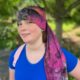 girl standing in front of trees wearing a tie dye nillynoggin eeg cap while testing for an eeg