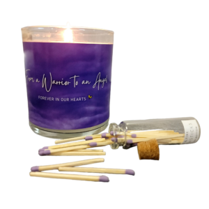 lit candle with purple label with the phrase From a Warrior to an Angel, Forever in our Hearts and a bottle of purple tipped matches