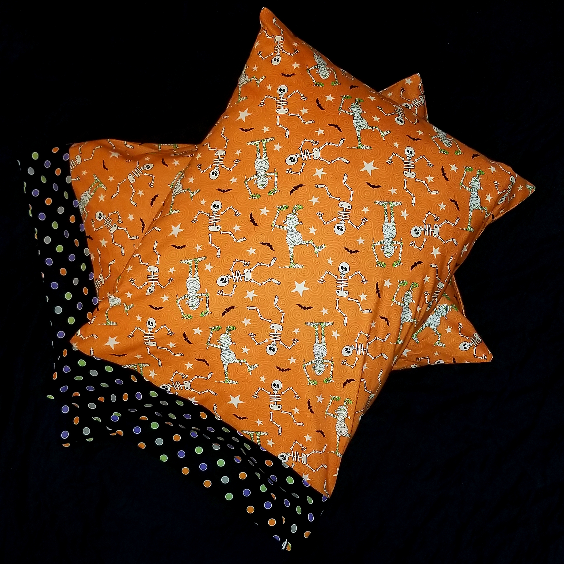 Halloween themed pillowcase with pattern of glow-in-the-dark skeletons and zombies, orange background, border of colorful dots on black