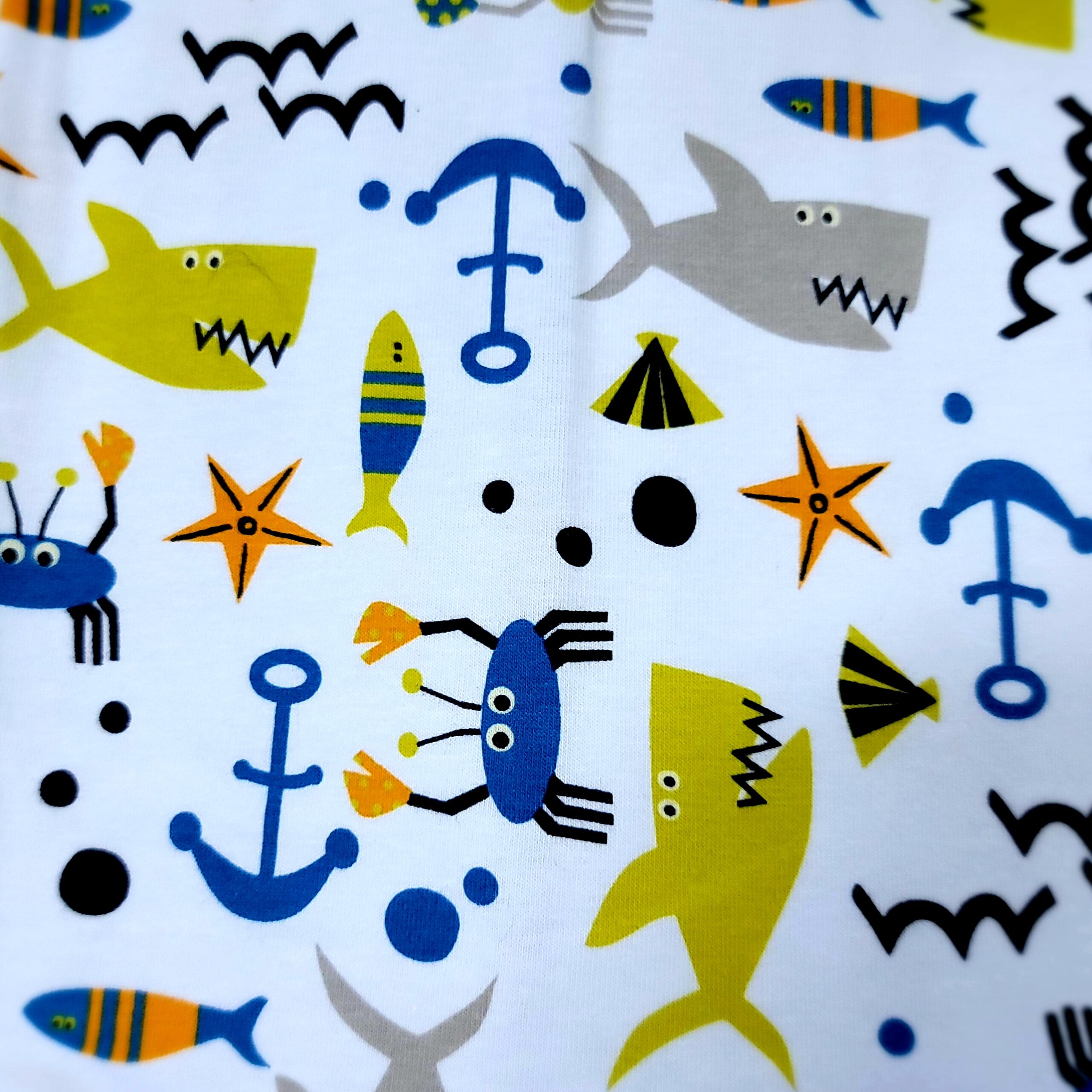 white fabric with green and grey sharks, blue crabs and anchors
