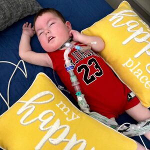 sleeping little boy with trach wearing a red outfit