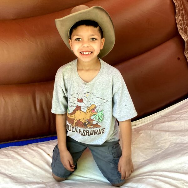 boy knealing smiling wearing a cowboy hat